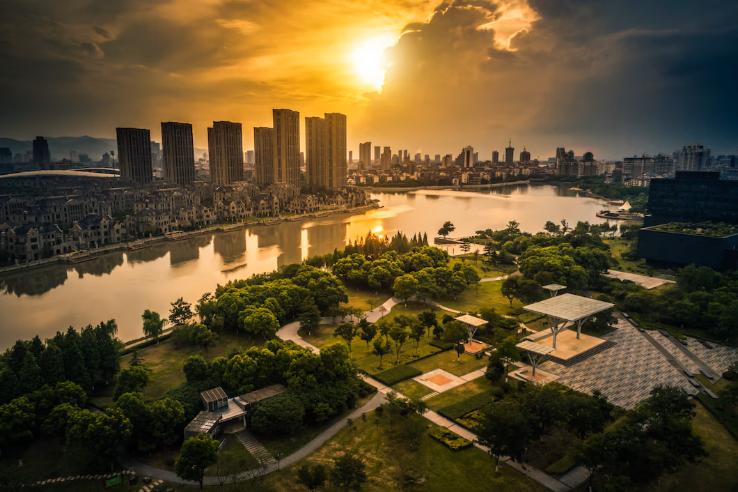 Modern township with park and lake at sunset.